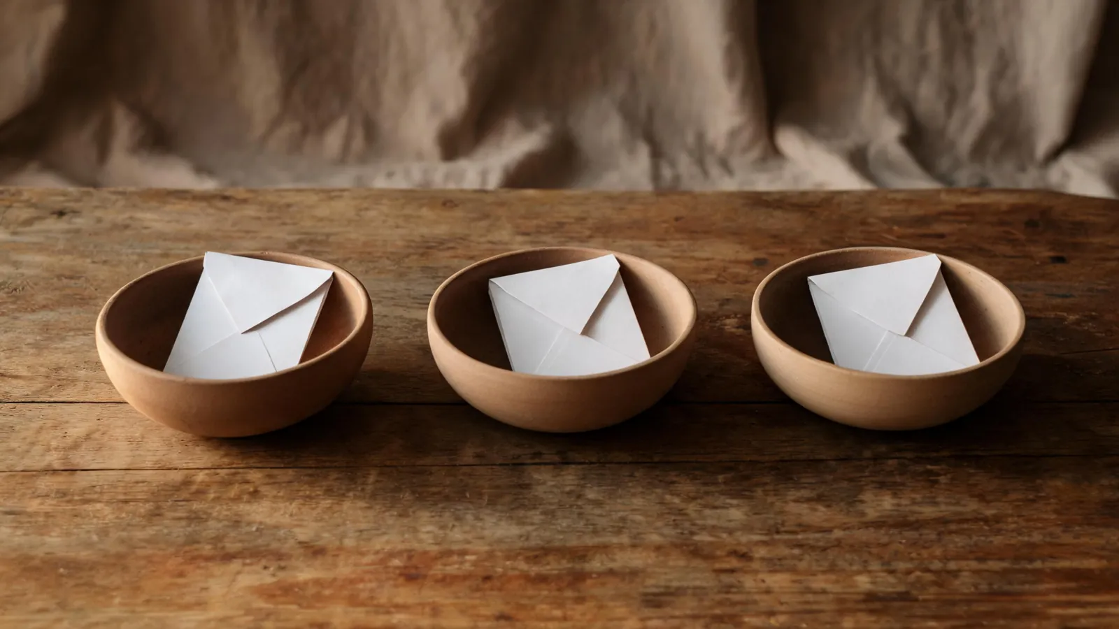 Three ceramic bowls with folded paper slips