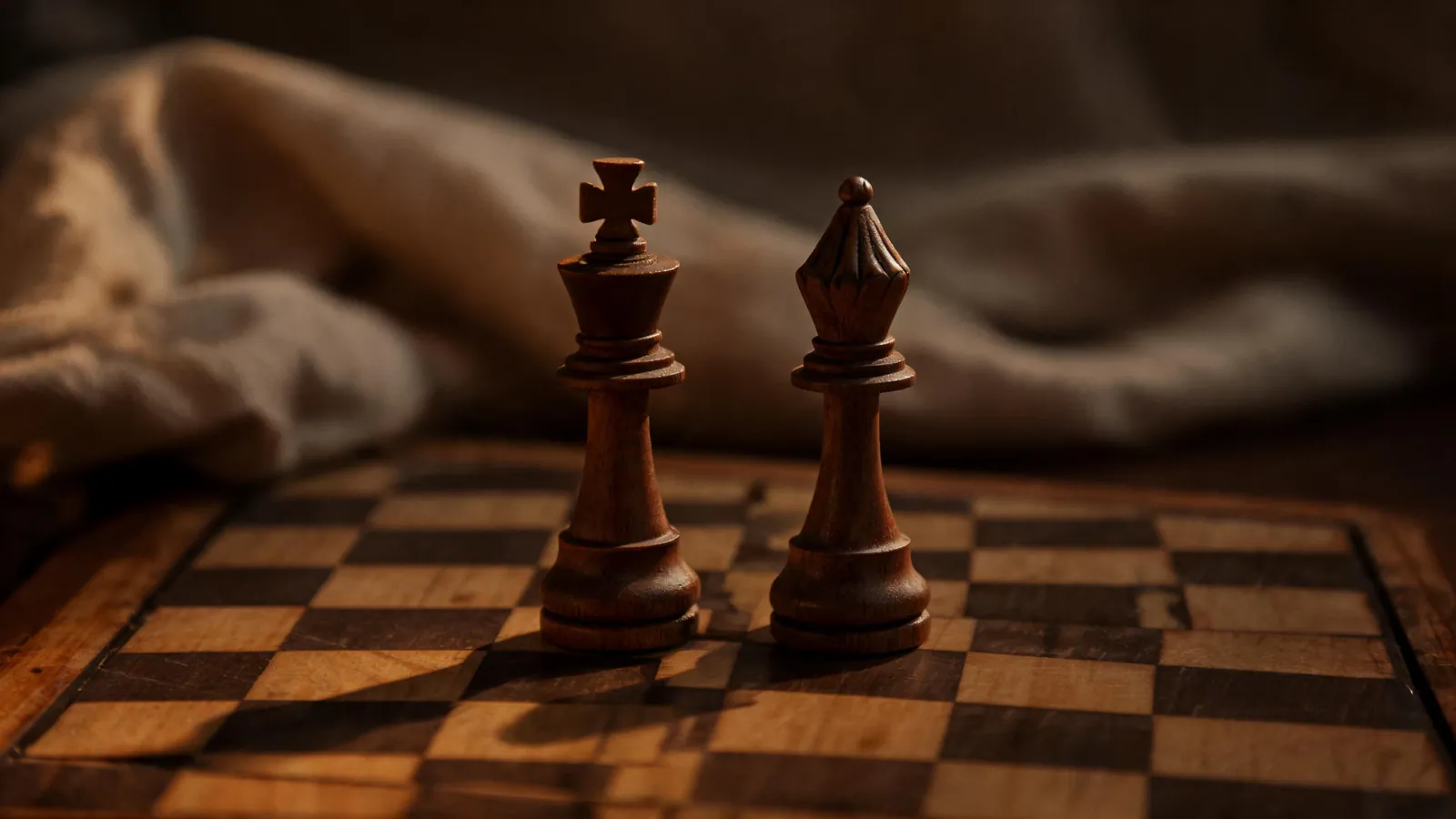 Two chess pieces on a wooden board in warm light
